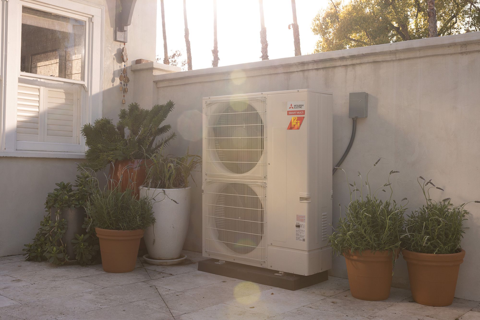 Mitsubishi SMART MULTI outdoor unit beside a home with a sunny courtyard